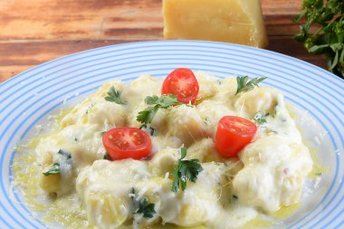 rondelli cannelloni delicious gnocchi pasta in white sauce with parmesan cheese, tomatoes, basil, herbs, healthy food of Italian and French cuisine.
