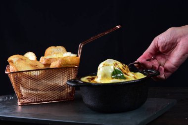 creamy rice with meat, melted cheese, meatballs served in an iron pan with bread