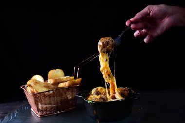 creamy rice with meat, melted cheese, meatballs served in an iron pan with bread