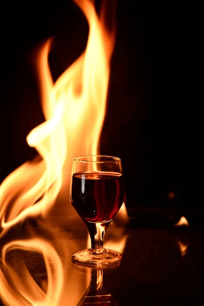 Kırmızı Şarabın Arka Planında Ateş Olan Bir Kadeh Konyak — Stok fotoğraf