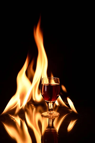 Kırmızı Şarabın Arka Planında Ateş Olan Bir Kadeh Konyak — Stok fotoğraf