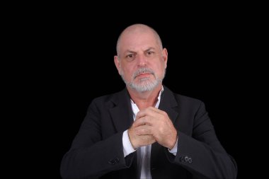 Siyah arka plana karşı beyaz gömlekli, orta yaşlı yakışıklı bir adam. Kendine güvenen iş adamı kutluyor