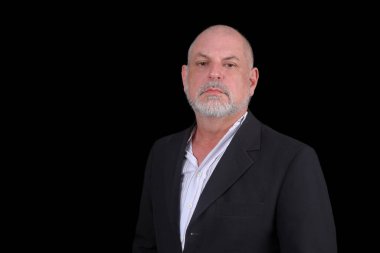 Siyah arkaplana karşı poz veren orta yaşlı yakışıklı bir adam. Kendine güvenen iş adamı