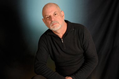 Siyah gömlekli beyaz sakallı beyefendi stüdyoya giriyor.