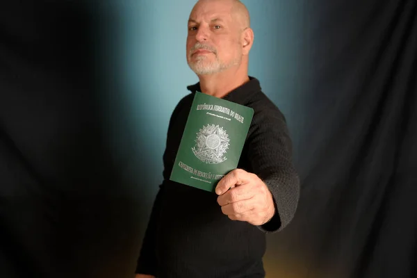 ブラジルのパスポートの書類を持っている白い髭の男黒いシャツの紳士 — ストック写真
