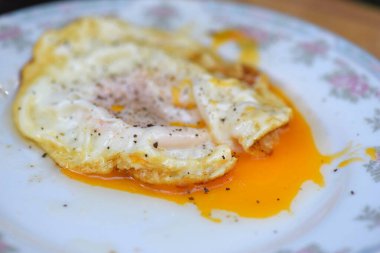Kızarmış tavuk yumurtası, yarı çiğ, tuzlu ve karabiberli. Vejetaryen olmayan sağlıklı yiyecekler beyaz tabakta servis ediliyor.