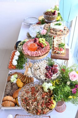 Çeşitli yiyeceklerle dolu bir parti masası peynirler meyve ve ekmek yer.