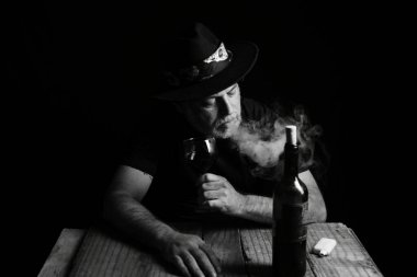 Şarap suratlı bir adam oturuyor. Siyah beyaz fotoğraf ve silüet yetişkin içkisi.