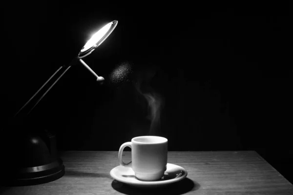 cup of coffee on wooden table with light coming from above image