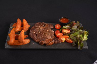 Köy usulü kızarmış patatesli ançolu biftek ve sebze soslu salata.