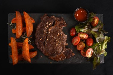 Köy usulü kızarmış patatesli ançolu biftek ve sebze soslu salata.