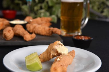 Bitki ve limon soslu kızarmış tavuk şeritleri aperatifi.