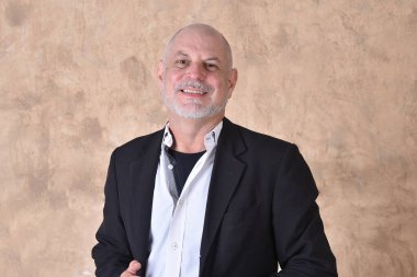 Siyah takım elbiseli yakışıklı bir adamın portresi. Beyaz gri sakallı, gülümseyen bir model.