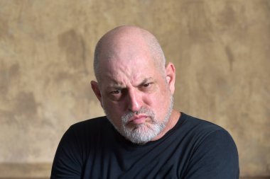 Kel beyaz sakallı yetişkin bir adamın portresi. Öfke ifadesi. Siyah giysili, düşünceli bir erkek model..