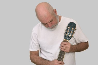 Beyaz sakallı ve kel kafalı yetişkin bir adamın portresi. Mutlu bir yüz ifadesi. Görüntü modelinde soyulmuş gitar çalan adam..