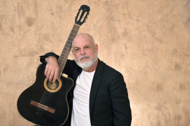 Beyaz sakallı ve kel kafalı yetişkin bir adamın portresi. Mutlu bir yüz ifadesi. Görüntü modelinde soyulmuş gitar çalan adam..