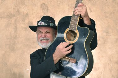 Beyaz sakallı ve kel kafalı yetişkin bir adamın portresi. Mutlu bir yüz ifadesi. Görüntü modelinde soyulmuş gitar çalan adam..