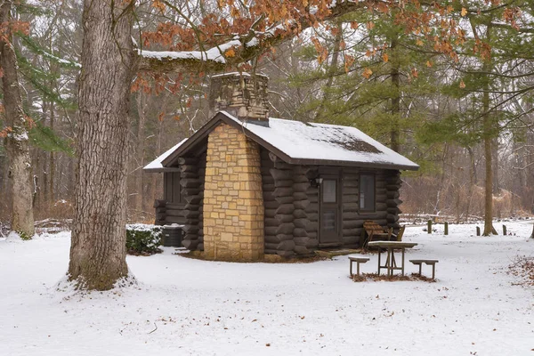 Cabin in the snow covered forest at White Pines Forest State Park, Illinois, USA.