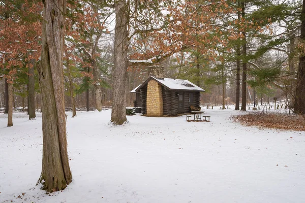Cabin in the snow covered forest at White Pines Forest State Park, Illinois, USA.