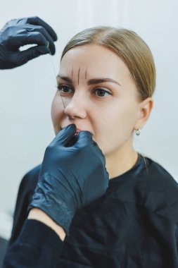 Kalıcı makyajdan önce profesyonel kaş haritalama işlemi sırasında genç bir kadın.