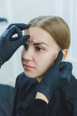 Kalıcı makyajdan önce profesyonel kaş haritalama işlemi sırasında genç bir kadın.