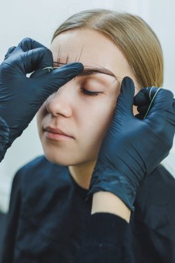 Kalıcı makyajdan önce profesyonel kaş haritalama işlemi sırasında genç bir kadın.