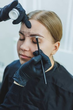 Kalıcı makyajdan önce profesyonel kaş haritalama işlemi sırasında genç bir kadın.