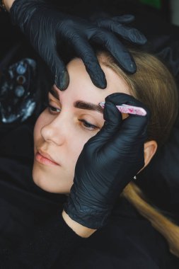 Çekici bir kadın yüzüne kaş makyajı yapan bir güzellik uzmanı.