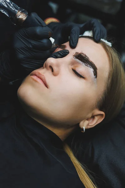 Permanent makeup. Beauty procedures. The master applies a tattoo on the eyebrows. Professional facial microblading. Women\'s cosmetology device.