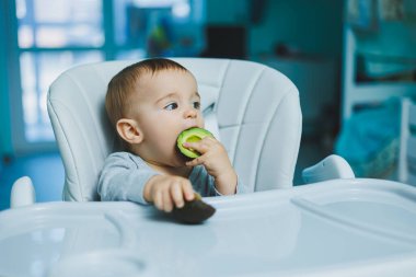 Küçük sevimli bebek avokado yiyor. Küçük çocuklar için vitamin ve sağlıklı yiyecekler. 8 aylık güzel bir çocuğun portresi