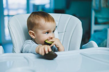 Küçük sevimli bebek avokado yiyor. Küçük çocuklar için vitamin ve sağlıklı yiyecekler. 8 aylık güzel bir çocuğun portresi