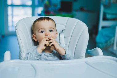 8 aylık küçük bir çocuk yerde oturuyor ve tahta oyuncaklarla oynuyor. Çocukların ekolojik oyuncakları