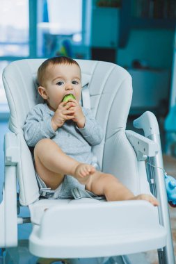 8 aylık küçük bir çocuk yerde oturuyor ve tahta oyuncaklarla oynuyor. Çocukların ekolojik oyuncakları