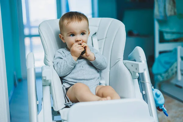 stock image A little 8-month-old boy is sitting on the floor and playing with wooden toys. Children's ecological toys