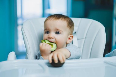 8 aylık küçük bir çocuk yerde oturuyor ve tahta oyuncaklarla oynuyor. Çocukların ekolojik oyuncakları