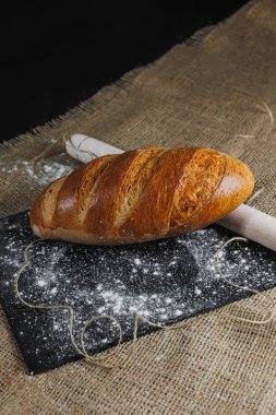 Ev yapımı ekmeğin un ve doğal tarım ürünlerinin üst görüntüsü. Sağlıklı ve lezzetli hamur işleri. Tam tahıllı ekmek, un. Kapat, koyu arkaplan