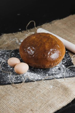 Sütlü ve koyu arkaplanda yumurtalı lezzetli yuvarlak çavdar ekmeği. Çıtır taze ekmek..