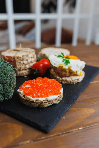 Diet rice breads, cherry tomatoes and fresh caviar and parsley on a dark background. Snack bread. View from above. Dietary fiber. Healthy Eating