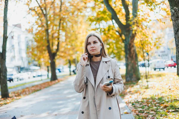 秋の公園を歩いていると 美しいサングラスの女性が電話で話しています 街の秋の路地で楽しい女の子 — ストック写真