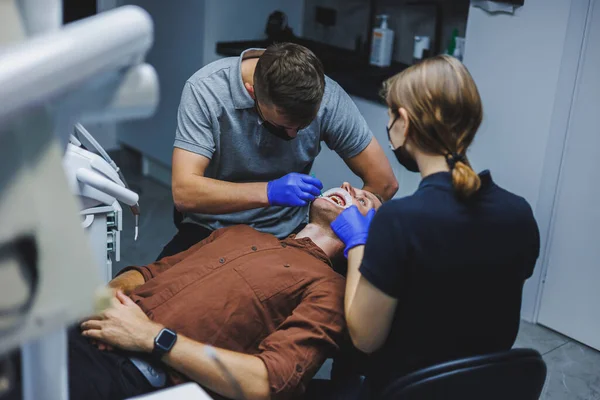 Лечение Зубов Молодой Человек Приеме Дантиста Врач Ассистент Лечат Зубы — стоковое фото