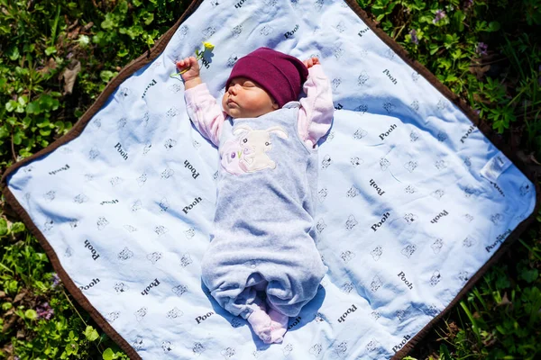 赤いキャップの赤ちゃんの写真の肖像画は 緑の芝生の上で遊ぶ白い上にあります 春は通りにあり 太陽は子供に輝いています — ストック写真