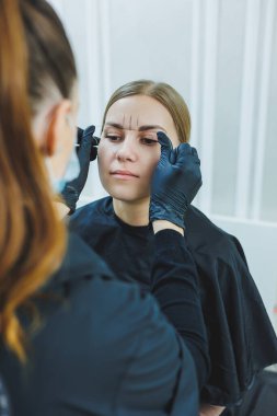 Kalıcı makyajdan önce profesyonel kaş haritalama işlemi sırasında genç bir kadın.