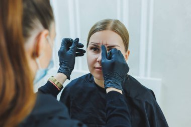 Young woman during professional eyebrow mapping procedure before permanent makeup clipart