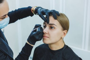 Kalıcı makyajdan önce profesyonel kaş haritalama işlemi sırasında genç bir kadın.