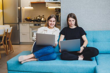 İki tatlı kadın oturma odasında dizüstü bilgisayar kullanarak arkadaşlarıyla görüntülü görüşme yapıyorlar. Arkadaşlar, arkadaşlık, birlikte zaman geçirmek. Kız arkadaşlar kanepede oturup film izliyorlar.