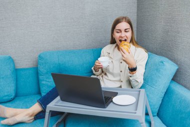 Kanepede otururken, bilgisayar başında çalışırken, blog yazarken ya da Webinar izlerken internetten e-posta haberlerini kontrol etmek için dizüstü bilgisayar kullanan gülümseyen kadın.