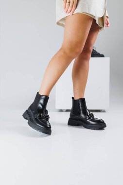 Metal tokalı kısa deniz botlu kadın bacakları, kadın deri ayakkabıları. Kadın ayakkabısı koleksiyonu.