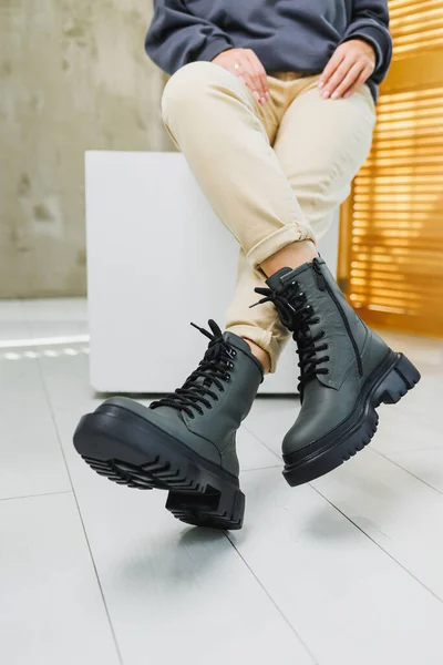 Fashionable women\'s stylish leather boots. Green women\'s genuine leather boots on feet close-up. New collection of winter shoes for stylish girls.