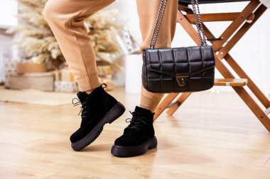 Siyah deri ayakkabılı kadın bacaklarının yakın çekimi. Kadın ellerinde siyah deri çanta. Kadın deri ayakkabılarının yeni sonbahar koleksiyonu 2022