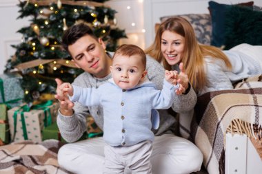 Noel ağacının yanında mutlu bir ailesi olan tatlı bir çocuk. Süslü bir Noel ağacının yakınındaki yatak odasında küçük bir çocuklu bir aile. Şenlikli yeni yıl atmosferi. Aile kutlaması